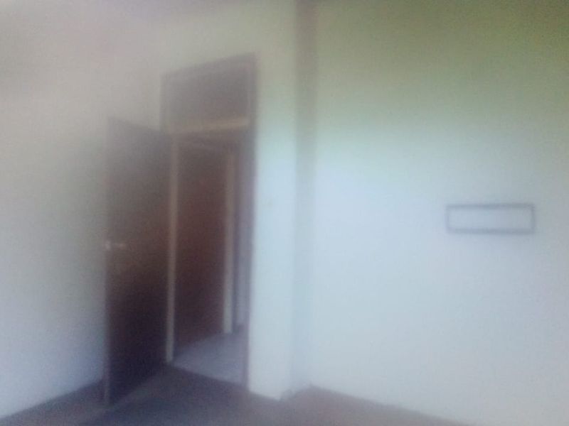 A blurry, low-quality interior view of an empty room with a doorway and a small wall-mounted fixture.