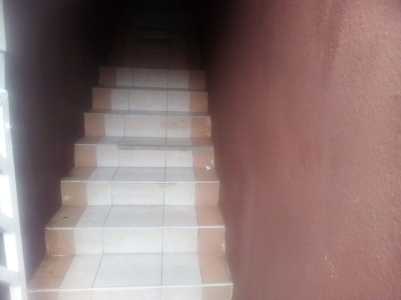 A narrow, dimly lit interior staircase featuring tiled steps with visible wear and damage to the tile edges.