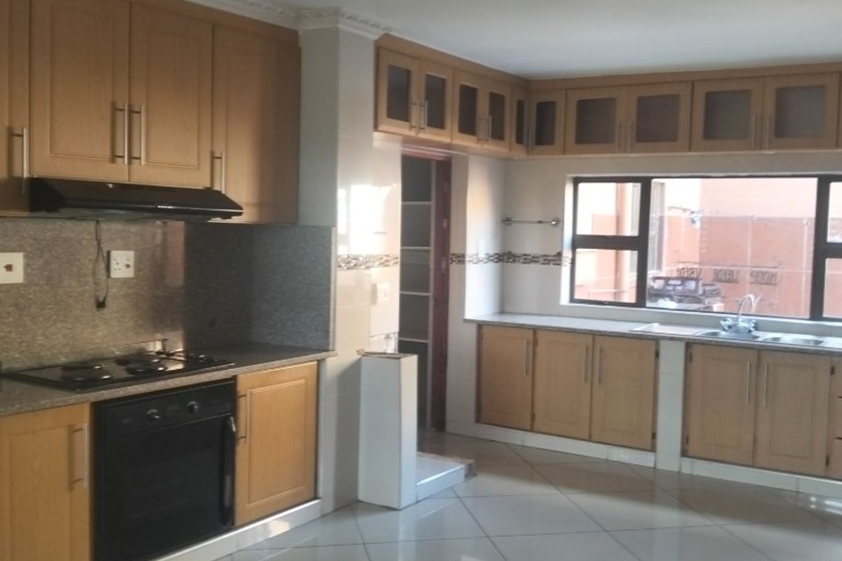 Spacious kitchen featuring light wood cabinetry, granite countertops, built-in oven, gas hob, and tiled flooring. The area is bright and well-maintained.