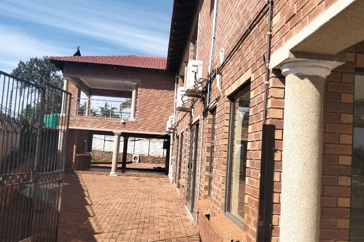 A side view of the property featuring face brick construction, paved pathways, and an elevated rear patio area with concrete columns.
