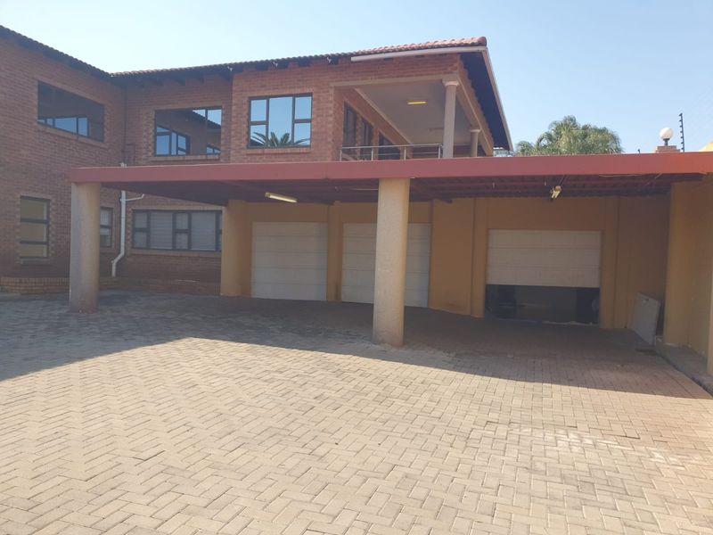 Front view of a multi-story brick house featuring a triple garage, paved driveway, and a covered carport area.