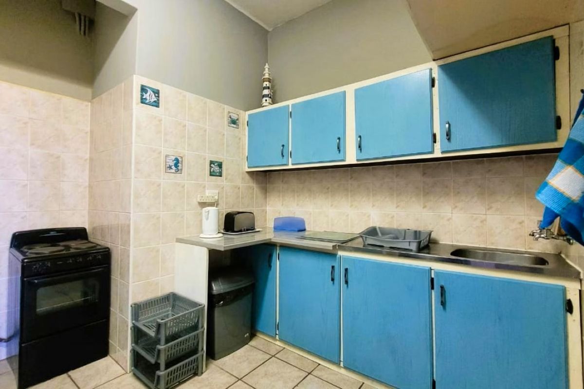 A functional kitchen featuring blue cabinetry, tiled backsplash, and a freestanding oven, offering potential for a modern renovation.