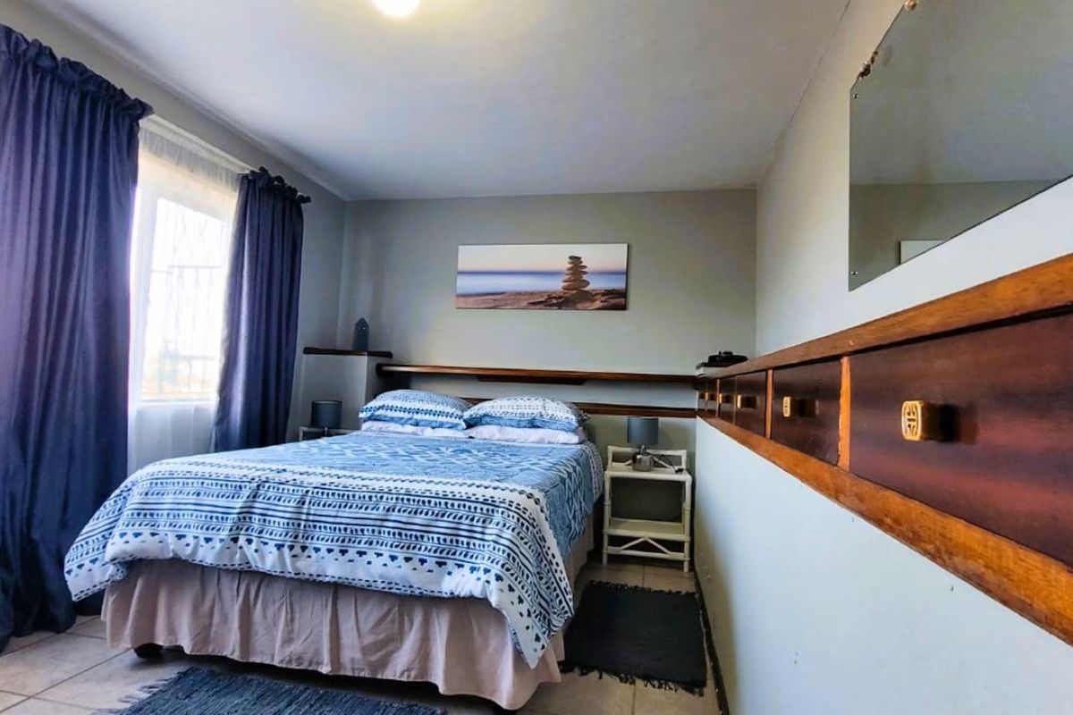 A bedroom featuring tiled flooring and a built-in wooden headboard with integrated storage shelving.