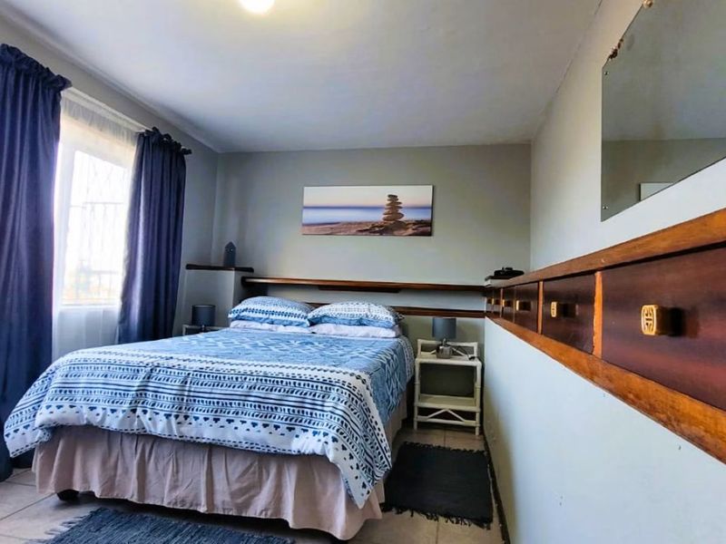 A bedroom featuring tiled flooring and a built-in wooden headboard with integrated storage shelving.