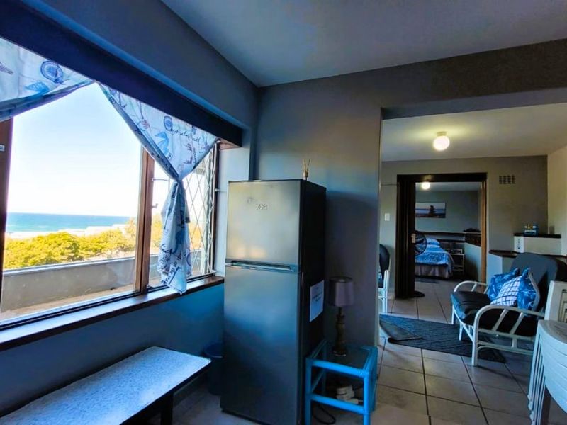 Open plan living area featuring tiled floors and large windows with ocean views, providing a bright and airy atmosphere.