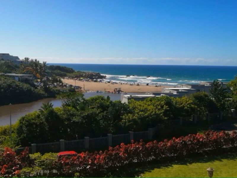 A scenic elevated view overlooking a coastal landscape, featuring a river estuary, sandy beach, and the ocean horizon.