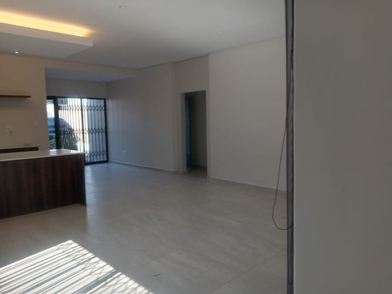 Spacious open-plan living area featuring modern tiled flooring, recessed ceiling lighting, and a kitchen island, offering a bright and versatile layout.