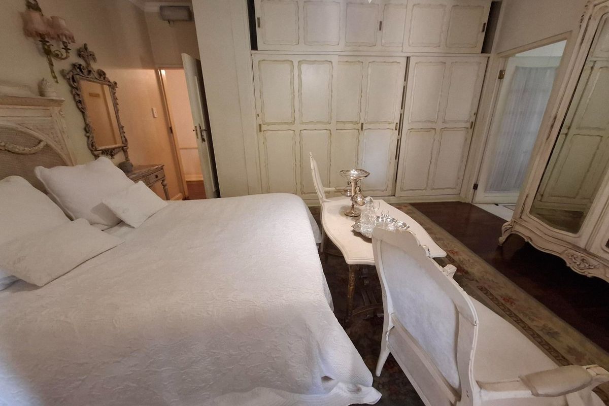 A spacious bedroom featuring extensive built-in cabinetry, crown molding, and dark hardwood flooring, offering a classic aesthetic with ample storage space.