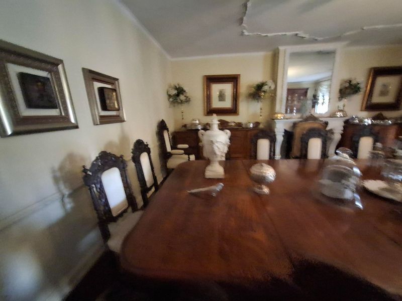 Formal dining room featuring decorative wall and ceiling molding, and a fireplace mantel. The ceiling shows signs of plaster damage.