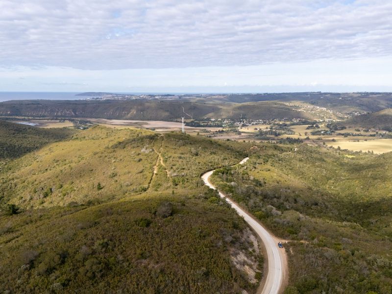 An aerial view of the expansive vacant land, showcasing the natural topography, surrounding hills, and access road.