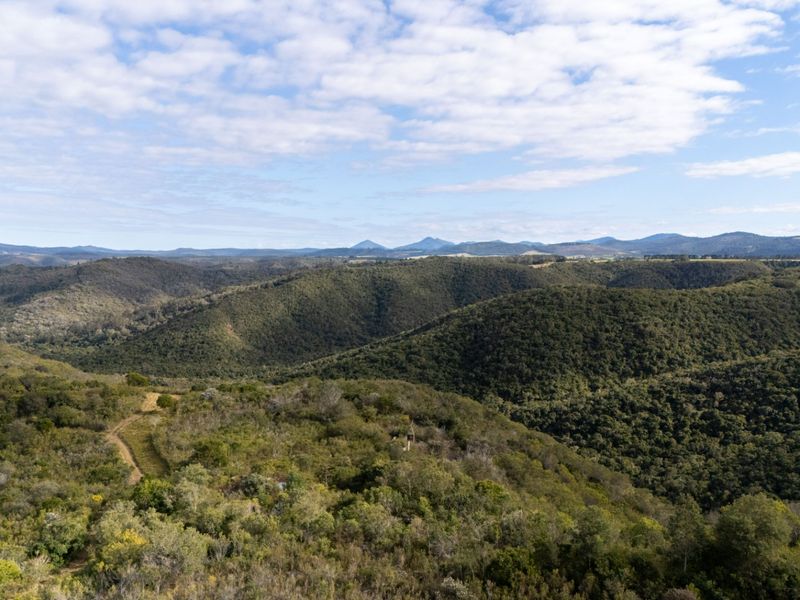 An expansive aerial view of the natural hilly landscape and dense native vegetation surrounding the vacant residential property.