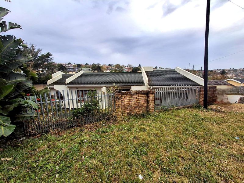 Front exterior view of a single-story residential property featuring a tiled roof, brick boundary wall, and steel palisade fencing.
