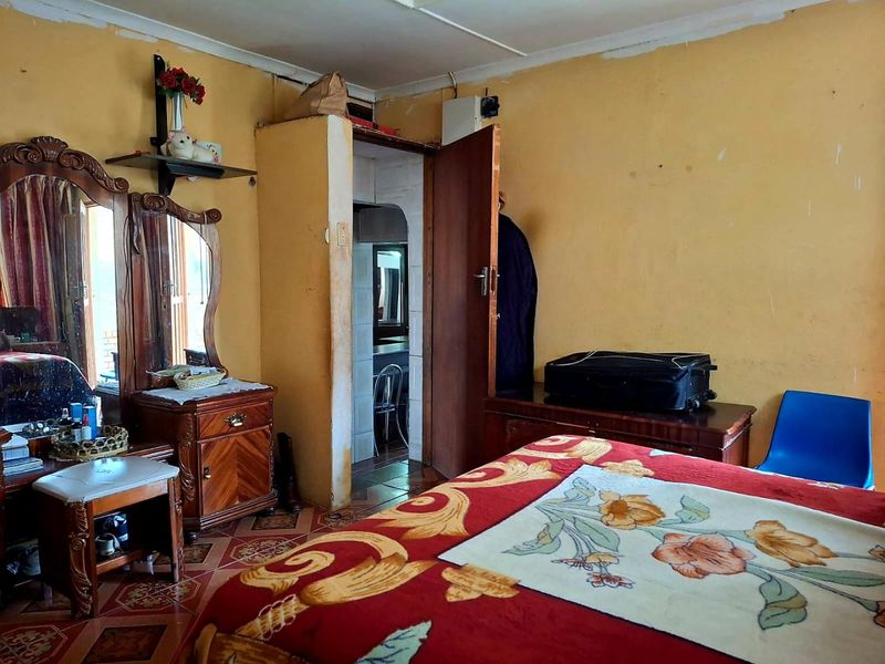A bedroom featuring tiled flooring and an internal doorway leading to an adjacent space, requiring cosmetic updates to the wall finishes.