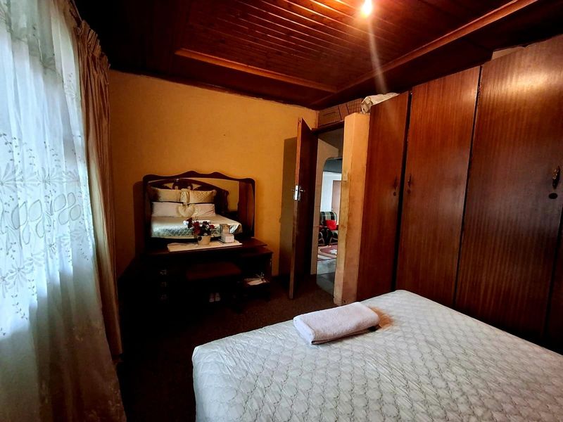 A bedroom featuring built-in wooden cupboards and a timber tongue and groove ceiling, requiring cosmetic updates to modernize the space.