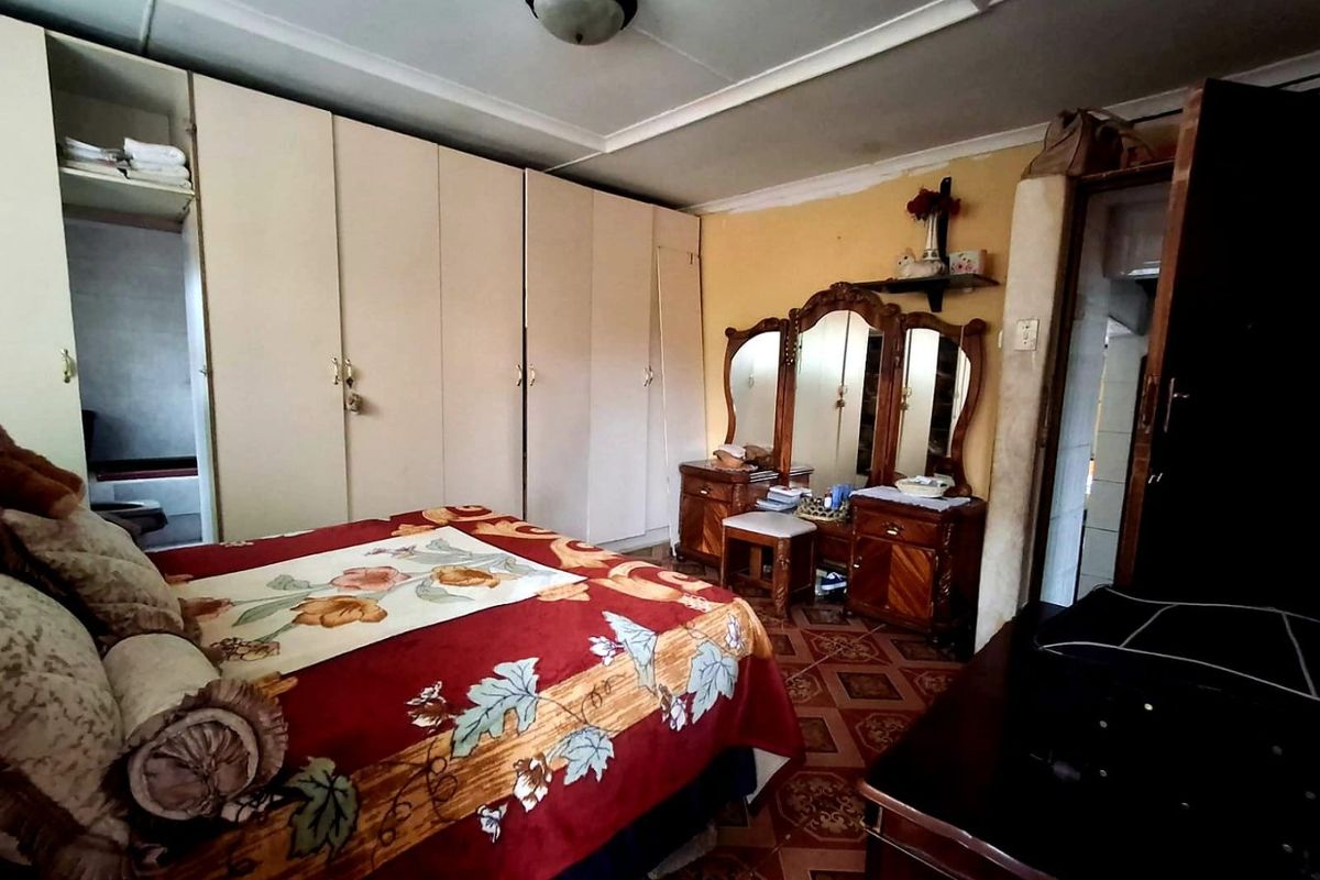 A bedroom featuring built-in cupboards, tiled flooring, and a ceiling light fixture. The space requires cosmetic updates to modernize the finishes.