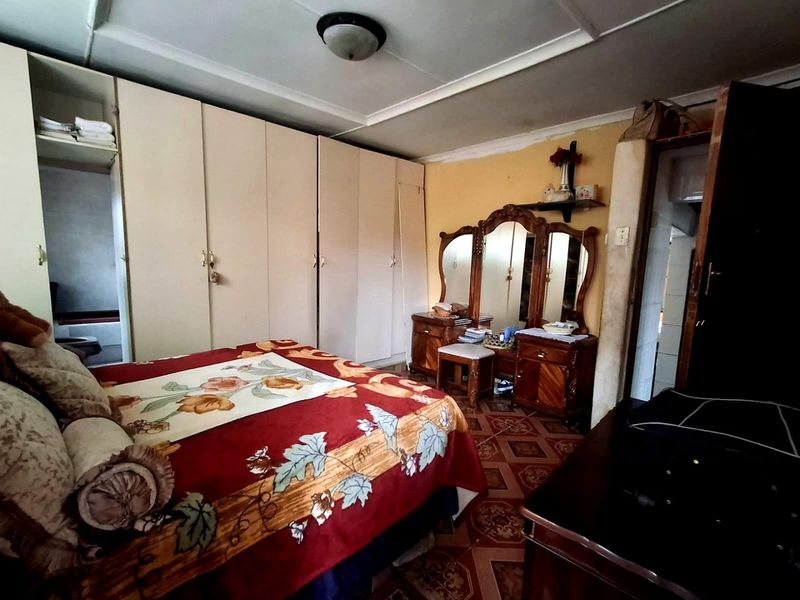 A bedroom featuring built-in cupboards, tiled flooring, and a ceiling light fixture. The space requires cosmetic updates to modernize the finishes.
