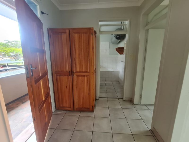 A functional hallway with tiled flooring, providing access to adjacent rooms and an exterior balcony area.