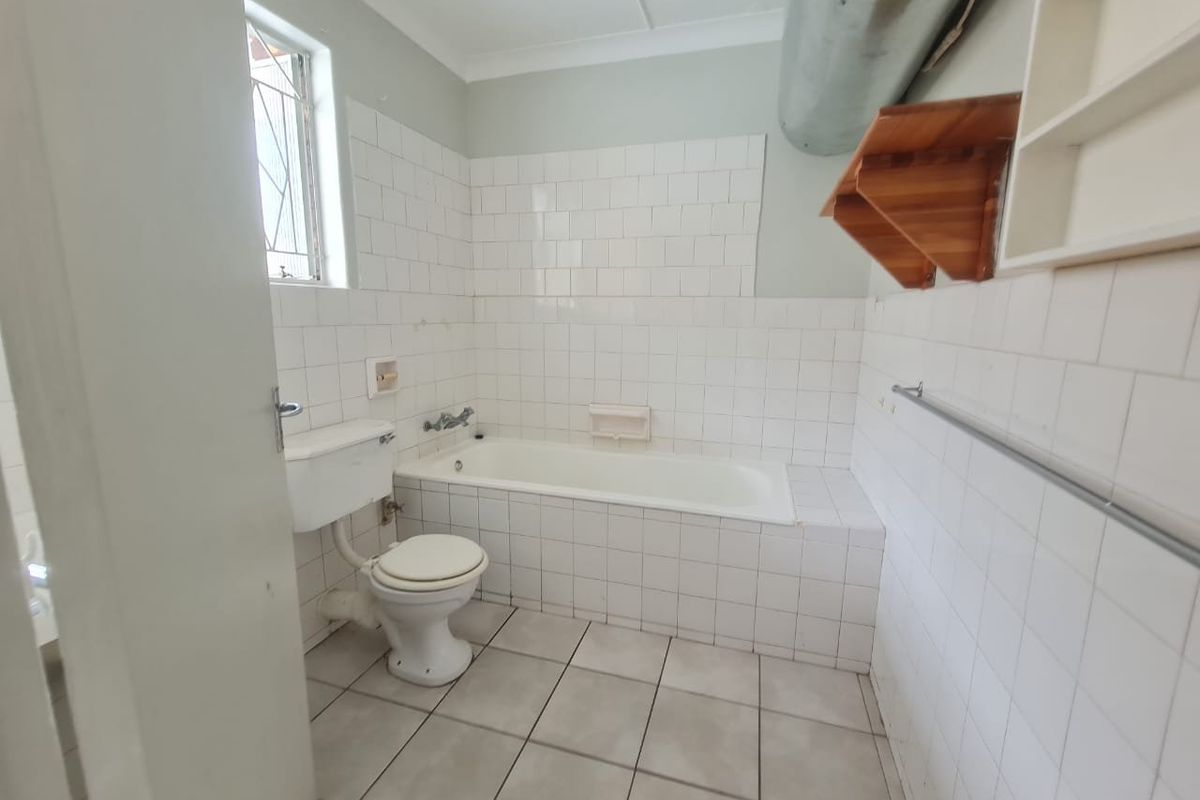 A functional bathroom featuring a bathtub, toilet, and tiled finishes. The space is ready for modernization and cosmetic updates to improve its overall appeal.