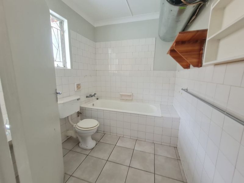 A functional bathroom featuring a bathtub, toilet, and tiled finishes. The space is ready for modernization and cosmetic updates to improve its overall appeal.