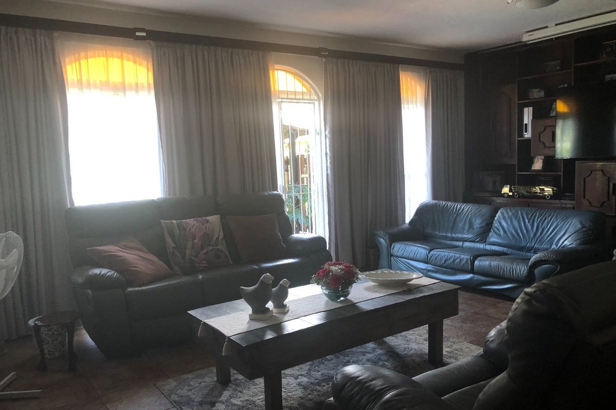 A living room featuring tiled flooring, built-in cabinetry, and arched windows with curtains, offering a traditional layout.