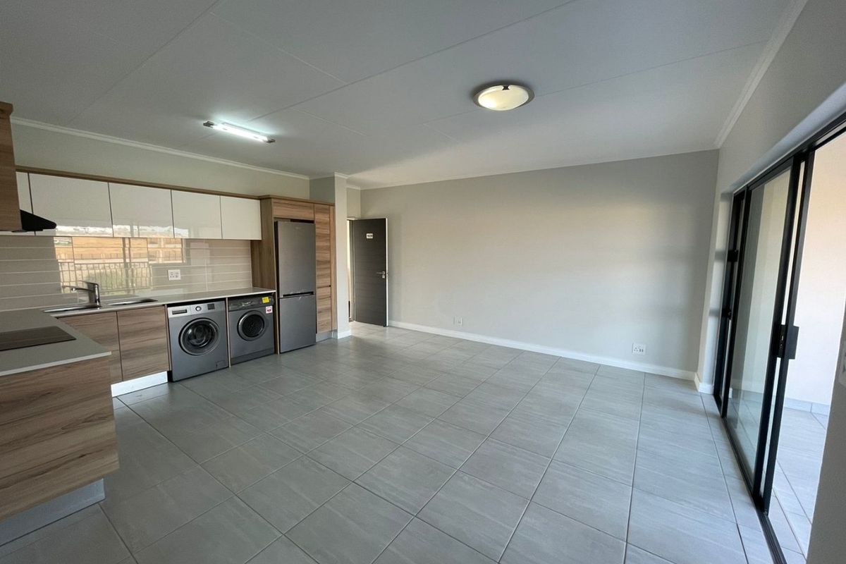 Modern open-plan living area featuring tiled floors, a contemporary kitchen with built-in cabinetry, and sliding glass doors leading to an outdoor space.