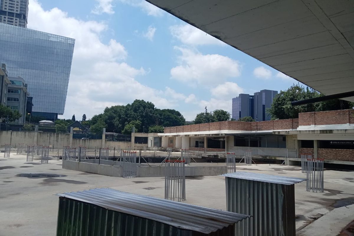 An elevated view of an unfinished construction site featuring a concrete slab, exposed reinforcement bars, and surrounding brick retaining walls.