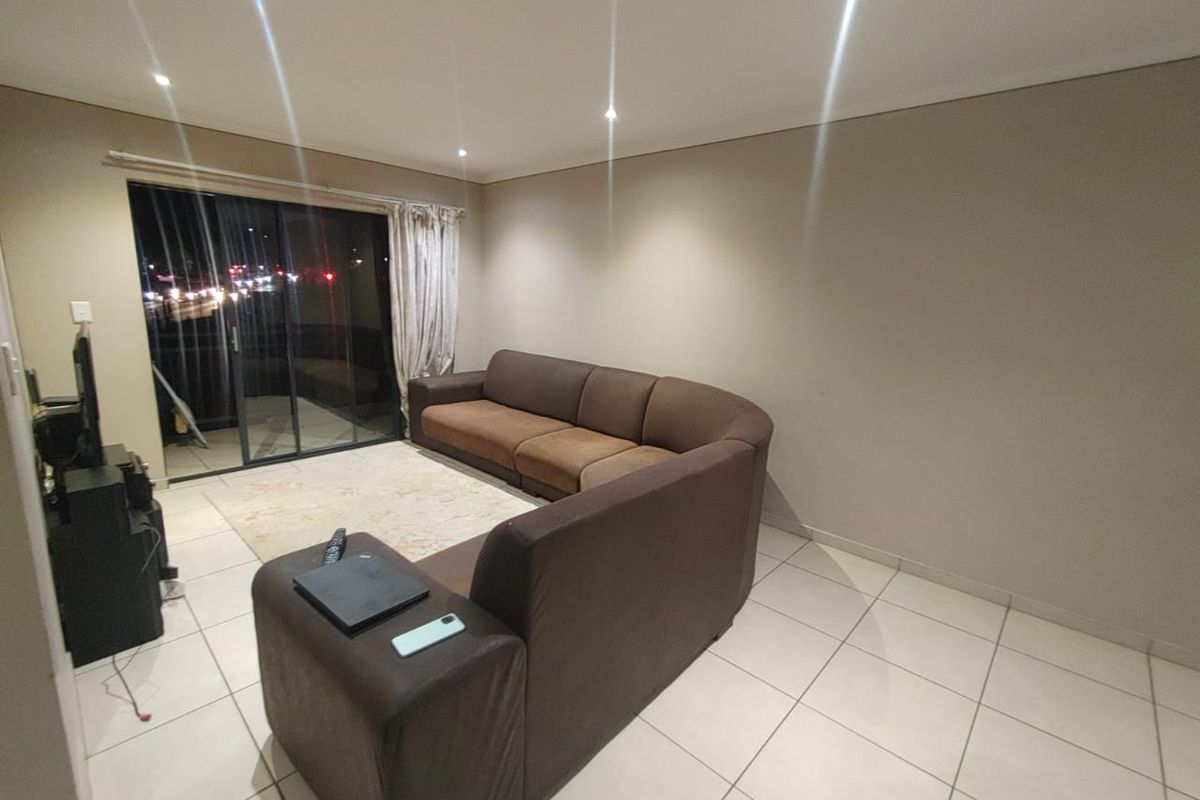 A living room featuring tiled flooring, recessed downlighting, and a large sliding glass door providing access to an outdoor area.