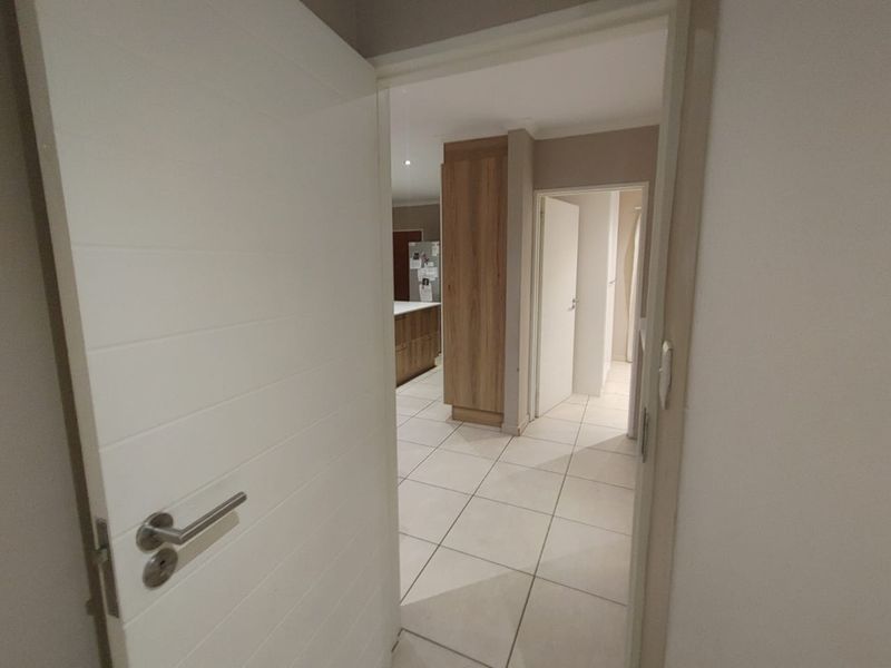 A bright hallway featuring tiled flooring and built-in cabinetry, providing access to adjacent living areas and rooms within the apartment.