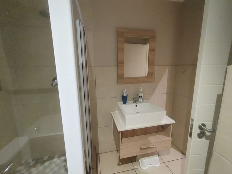 A functional bathroom featuring a modern vessel sink vanity, wall-mounted mirror, and a separate shower enclosure with tiled finishes.