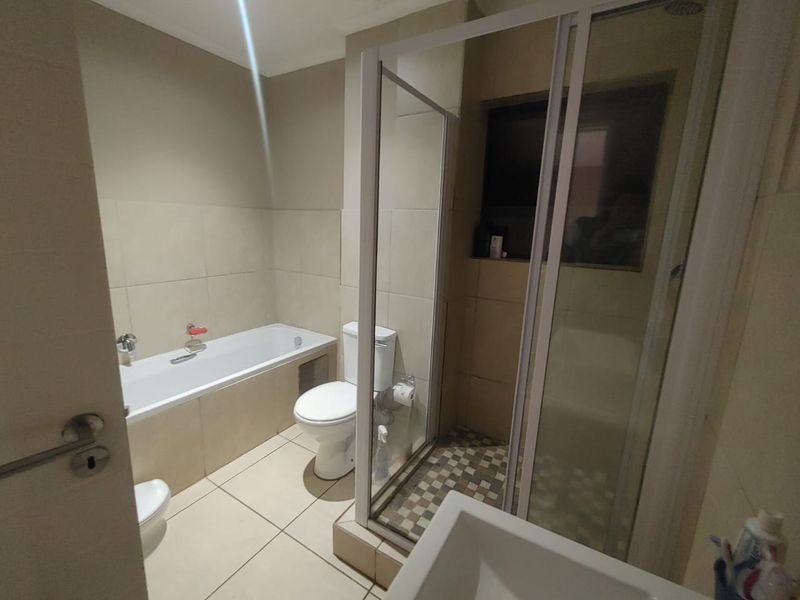 A functional bathroom featuring a built-in bathtub, separate shower enclosure, toilet, and tiled finishes throughout.
