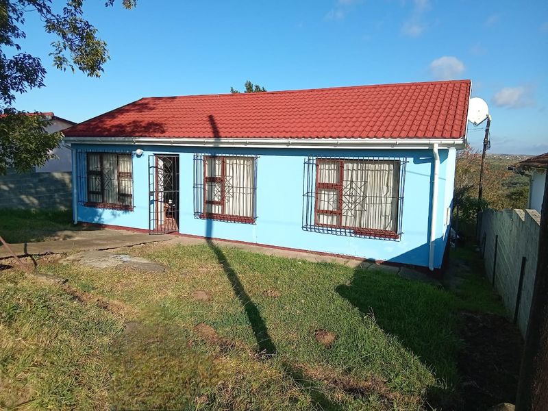 Front view of a single-story house featuring a red tiled roof, blue exterior walls, and security bars on the windows.