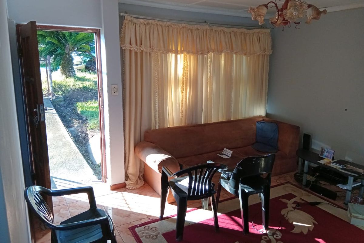A living room area featuring tiled flooring and direct access to the exterior, providing natural light through the doorway.