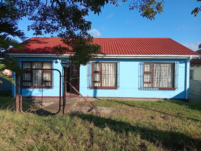 Front elevation of a single-story house featuring a red tiled roof, blue exterior walls, and security bars on the windows.