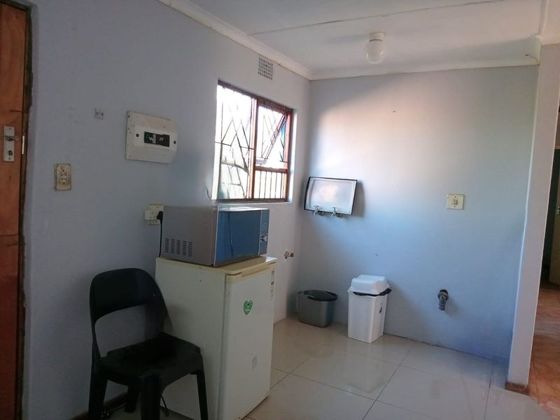 A functional laundry area featuring tiled flooring, security bars on the window, and existing plumbing connections for utility appliances.