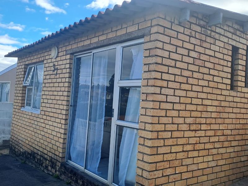 Exterior view of a face brick house featuring aluminium window frames and a sliding glass door entrance.