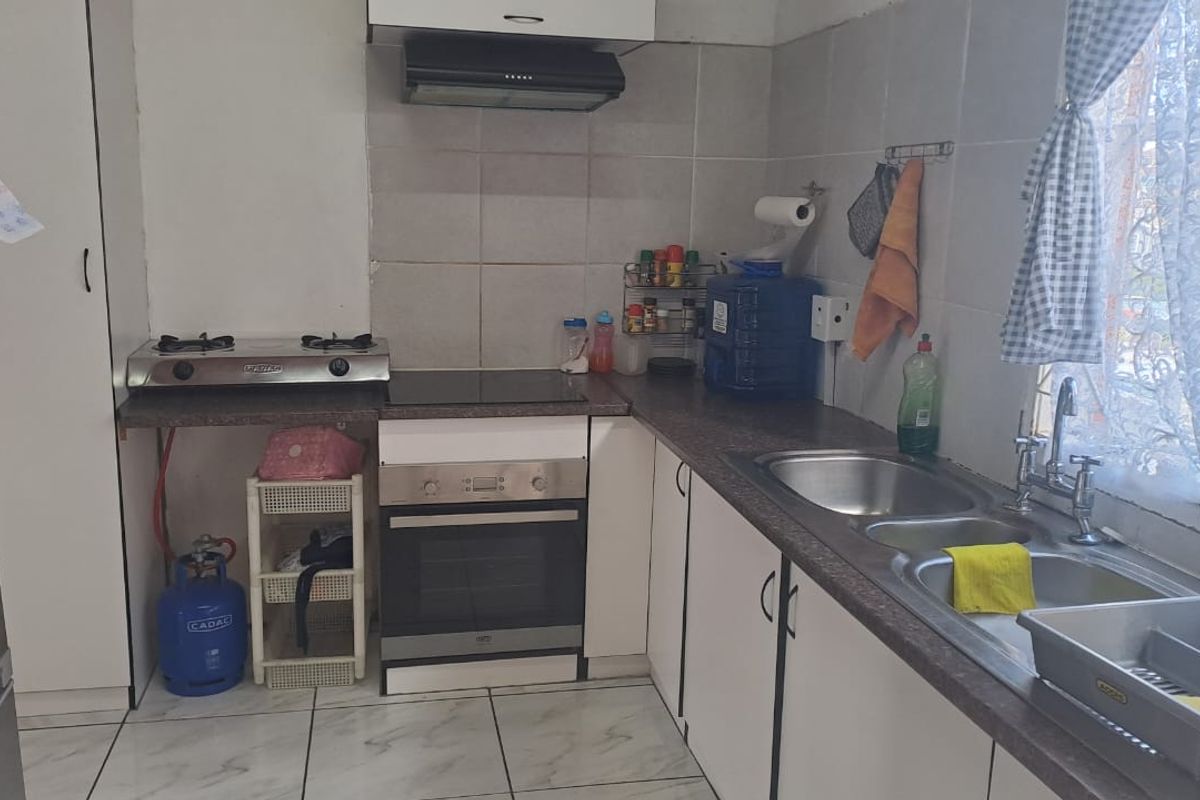 A functional kitchen featuring built-in oven, extractor fan, double bowl sink, and tiled splashbacks with ample counter space.