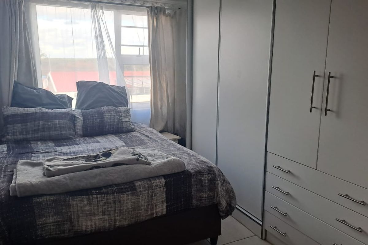 A functional bedroom featuring built-in cupboards and tiled flooring, offering a clean and practical living space.
