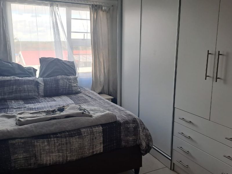 A functional bedroom featuring built-in cupboards and tiled flooring, offering a clean and practical living space.