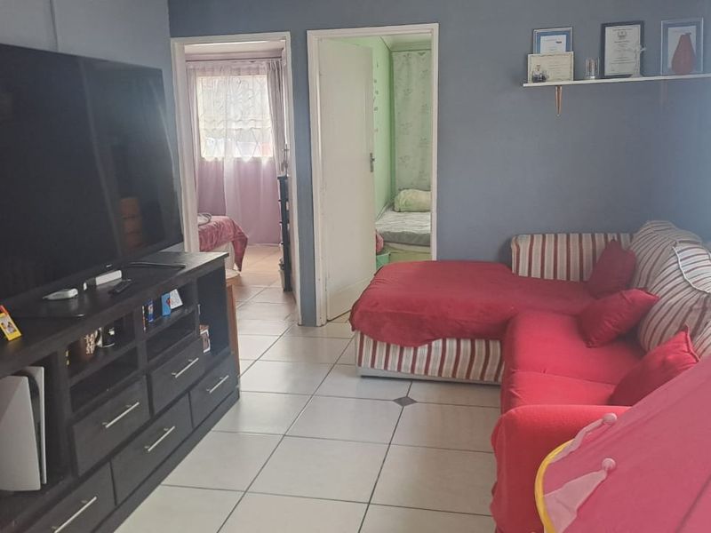 A living room featuring ceramic floor tiles and access to adjacent bedrooms.