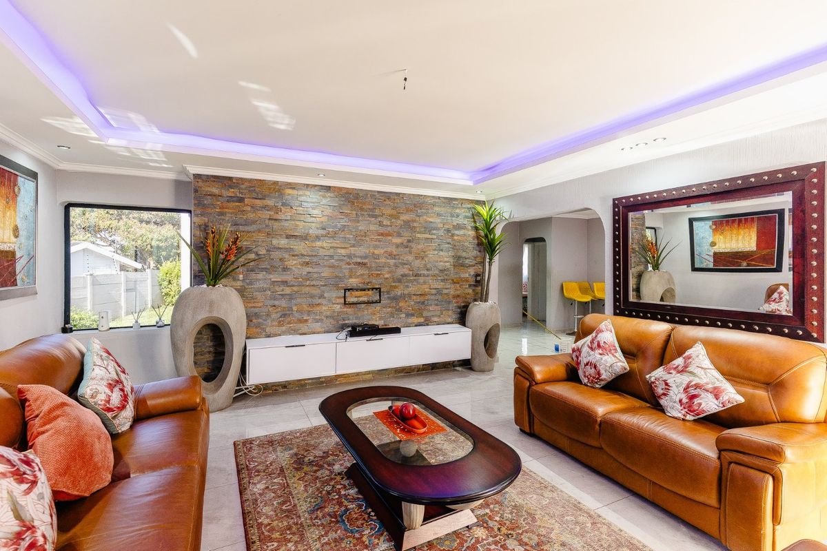 A modern living room featuring a textured stone accent wall, recessed LED ceiling lighting, and polished tiled flooring.