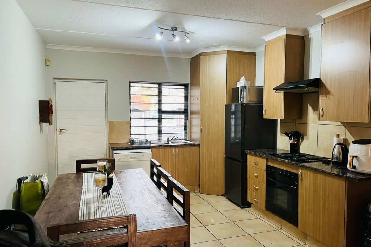 A functional kitchen featuring wood-finish cabinetry, tiled flooring, and integrated cooking appliances, providing a practical layout for daily meal preparation.