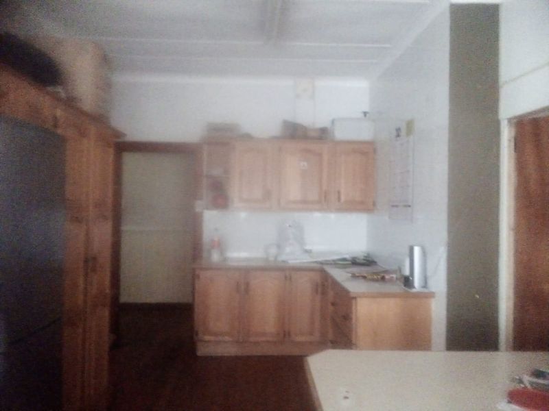 A dated kitchen featuring wooden cabinetry and laminate countertops, offering a functional layout with potential for modernization.