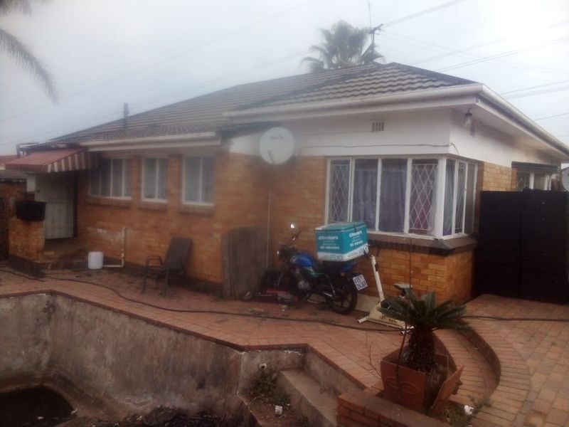 Rear exterior view of a brick house featuring a paved patio area and an in-ground swimming pool.