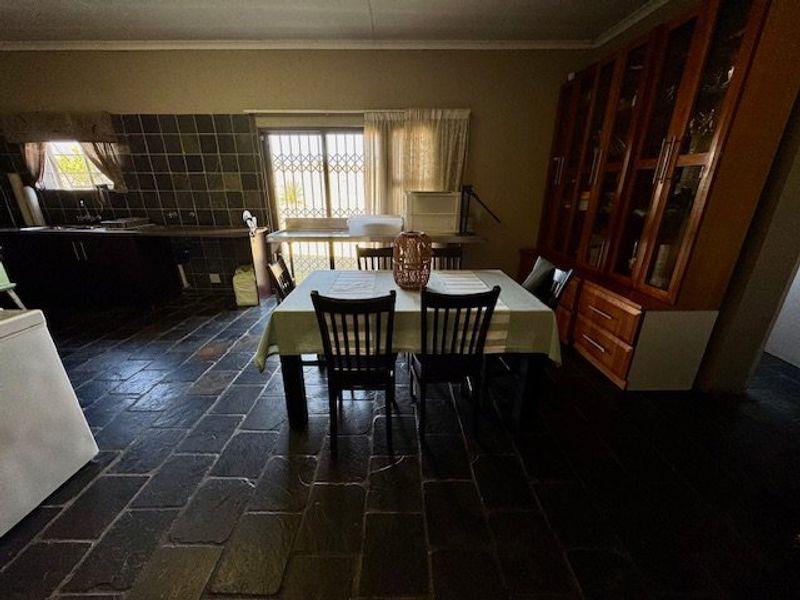 Open plan living and dining area featuring dark slate tile flooring, built-in cabinetry, and access to the exterior via a sliding glass door.