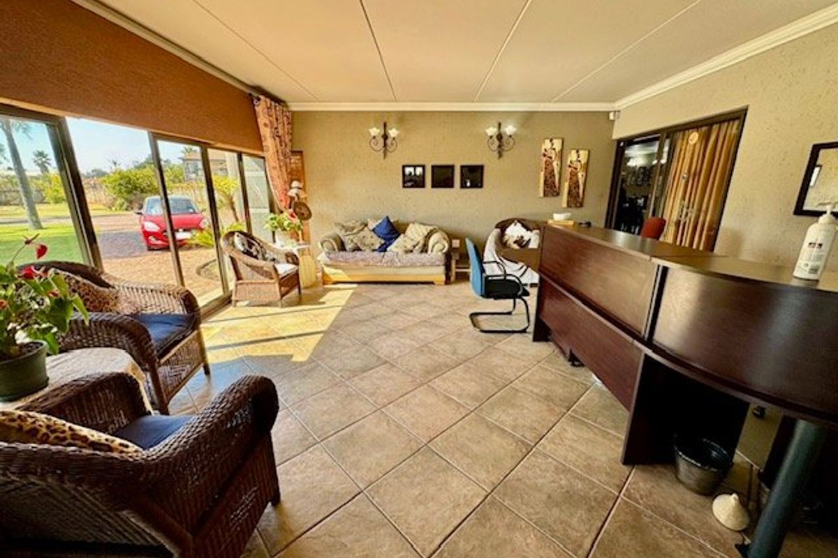 Spacious living area featuring large sliding glass doors, tiled flooring, and wall-mounted lighting fixtures, suitable for a lounge or reception space.