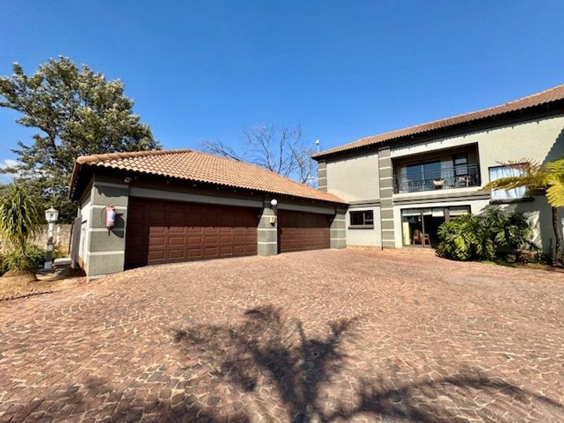 Front exterior view of a two-story house featuring a double garage, paved driveway, and an upper-level balcony.