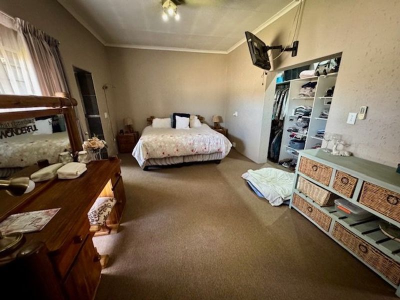 Spacious bedroom featuring carpeted flooring, a built-in wardrobe, and a wall-mounted television bracket.