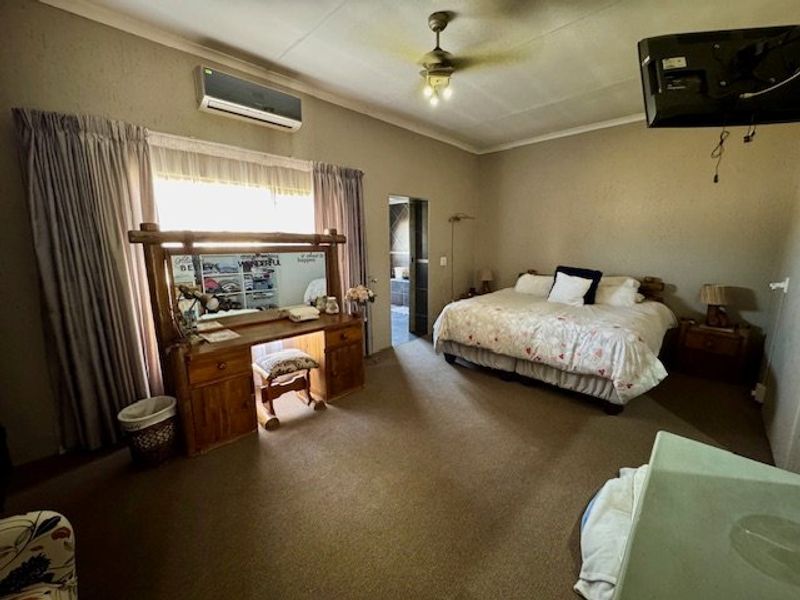 Spacious bedroom featuring carpeted flooring, a ceiling fan, and a wall-mounted split-system air conditioner.