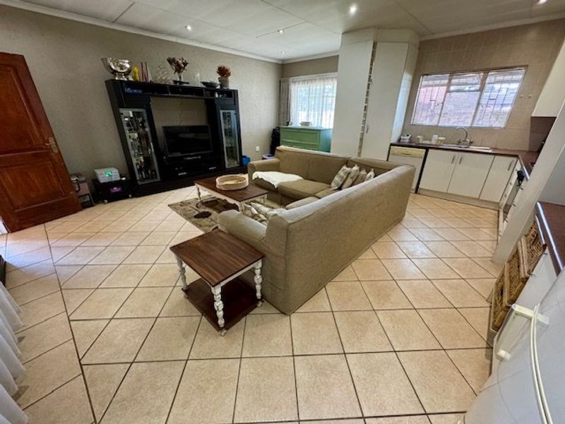 Open-plan living area featuring tiled flooring, recessed lighting, and a functional kitchen space with built-in cabinetry and sink.