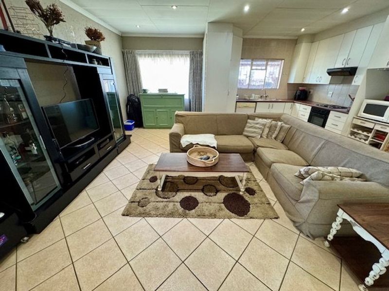 Open-plan living and kitchen area featuring tiled flooring, recessed lighting, and functional built-in cabinetry with integrated appliances.